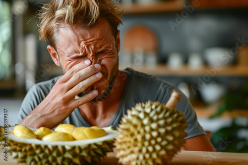 Man grimacing at durian fruit smell.
 photo