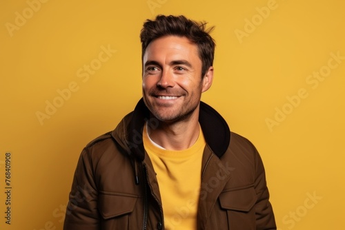 Portrait of a smiling young man in a brown jacket over yellow background