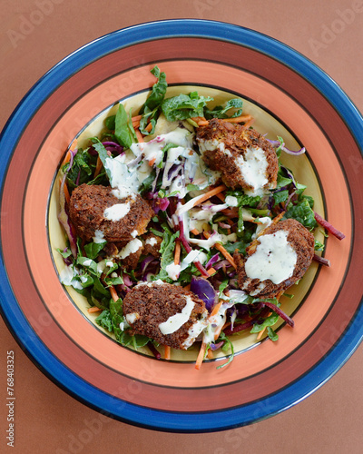 A garden salad with chickpeas koftas drizzled with yogurt and chia dressing.