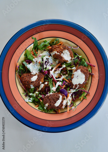 A garden salad with chickpeas koftas drizzled with yogurt and chia dressing.