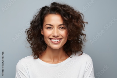 Portrait of young happy smiling woman with curly hair, over grey background