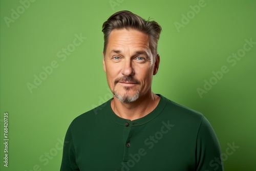 Portrait of handsome mature man with beard and mustache on green background