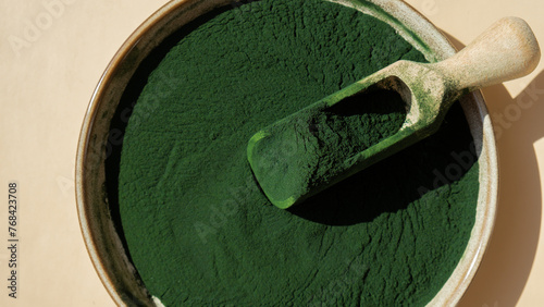 Natural organic green spirulina algae powder in bowl and wooden spoon on neutral background. Chlorella seaweed vegan superfood supplement source and detox. Copy space Healthy nutritional antioxidant © anna.stasiia