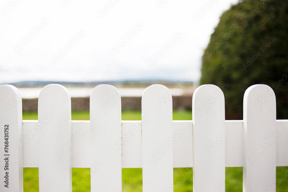 White wooden picket fence, in front of garden with sea view - a home by the sea theme White wooden picket fence, in front of garden with sea view - a home by the sea theme