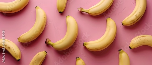   A group of bananas resting on a pink background beside a banana peel and a banana peel in the center of the image