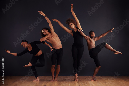 Performance, drama and portrait of group dancing, creative and art of body, moving and passion. Black background, men and women with pride, confident and people with balance, stage and ballet