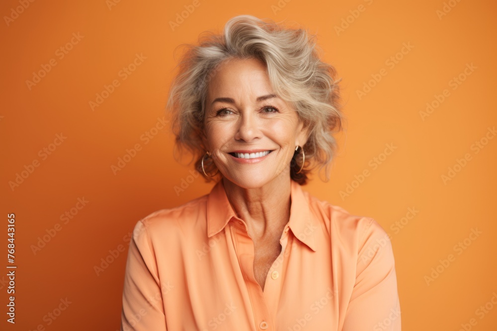 Portrait of smiling senior woman looking at camera isolated on orange background Portrait of smiling senior woman looking at camera isolated on orange background