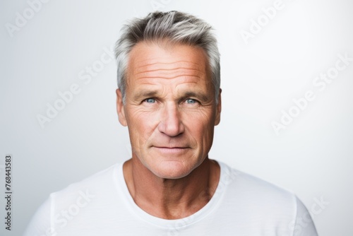 Portrait of mature man looking at camera with serious expression on grey background