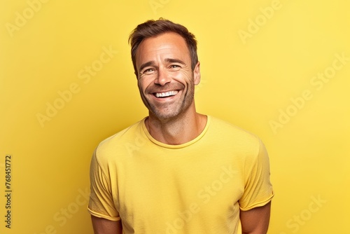 Portrait of happy young man in yellow t-shirt on yellow background