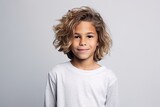 Portrait of a cute little boy with flying hair over grey background