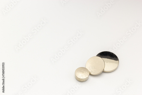Three circular lithium batteries of different sizes on a white background.  (ID: 768453953)