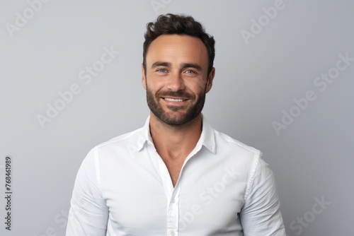 Portrait of handsome young man looking at camera and smiling while standing against grey background