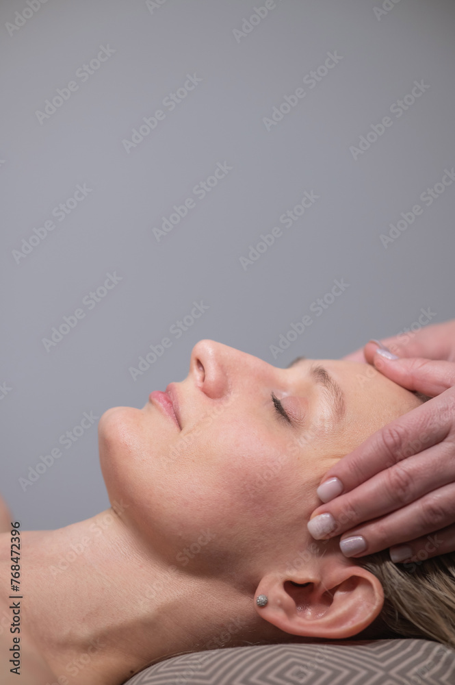 Caucasian woman undergoing a head and face massage procedure. Vertical photo. Caucasian woman undergoing a head and face massage procedure. Vertical photo.
