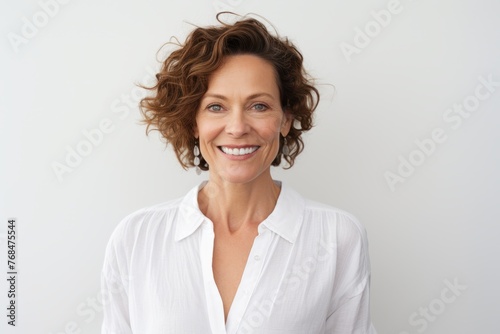 Portrait of beautiful middle-aged woman with curly hair  smiling at camera.