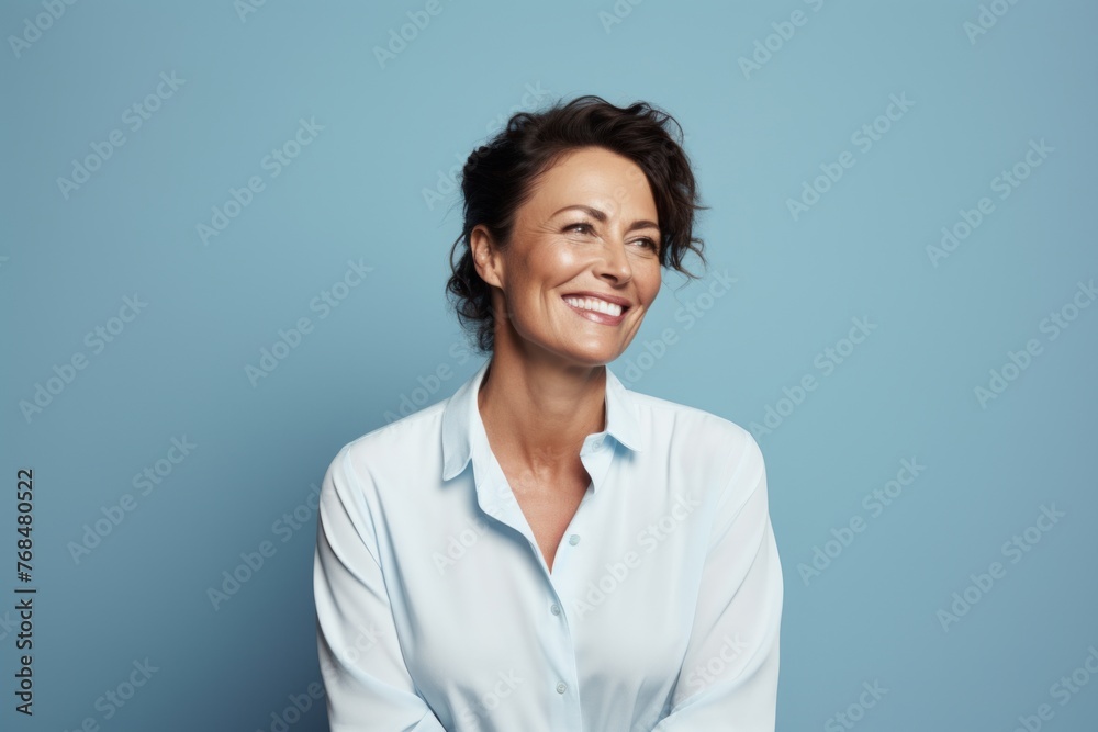 Portrait of smiling middle aged businesswoman in shirt on blue background Portrait of smiling middle aged businesswoman in shirt on blue background