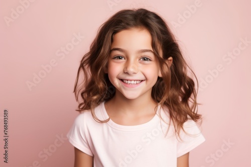 Portrait of a cute little girl with long hair on a pink background