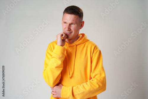 Thoughtful caucasian young male touching chin with hand thinking on gray background