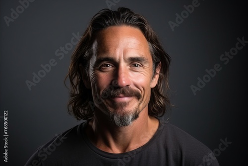 Handsome middle age man with long hair and beard on a dark background © Chacmool
