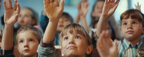 Children at classroom with hands up.