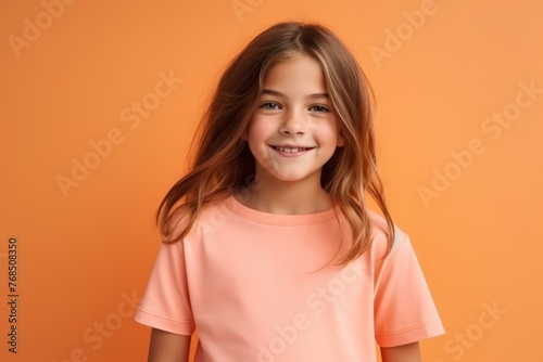 Portrait of a cute little girl smiling at camera over orange background