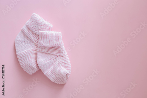 Knitted booties for a newborn on a pink background. Shoes for newborns