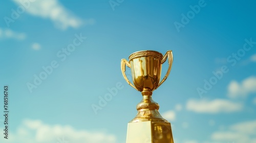 A gold trophy cup showcased against a bright blue sky with fluffy clouds.