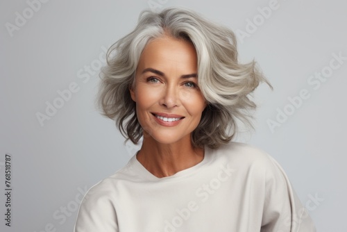 Beautiful middle aged woman with grey hair smiling and looking at camera