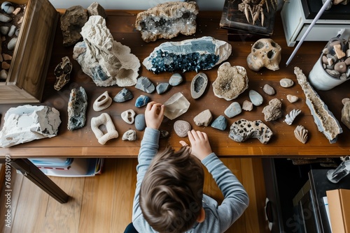 kid organizing a collection of rocks and fossils on a spacious desk © altitudevisual