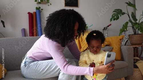 Proyecto sin título 11A cheerful mother captures a moment with her focused toddler, bonding over technology. Engaged Mother Taking a Selfie with Her Curious Toddler photo