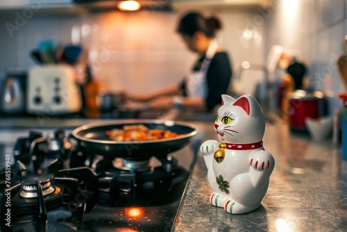 maneki neko on a kitchen counter, person cooking nearby photo