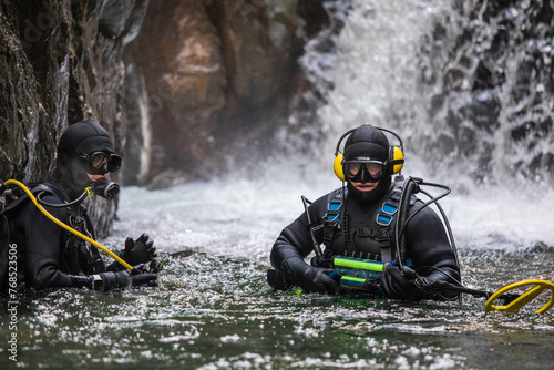 Team of divers use metal detecting equipment to find gold in a river photo