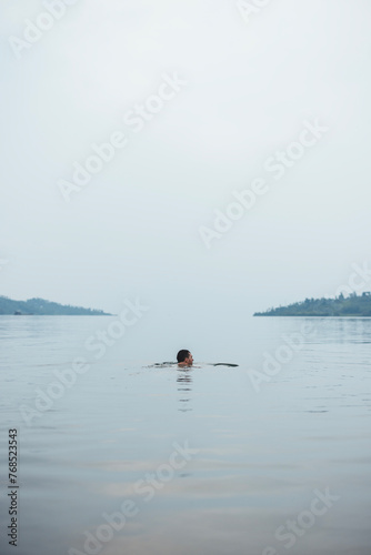 Man swims in peaceful waters of Lake Kivu, Rwanda photo