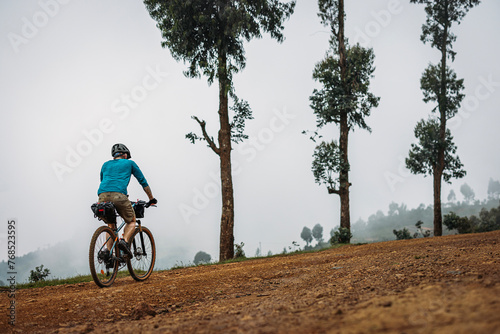Mountain biker cycles along gravel road in the mountains of Rwanda