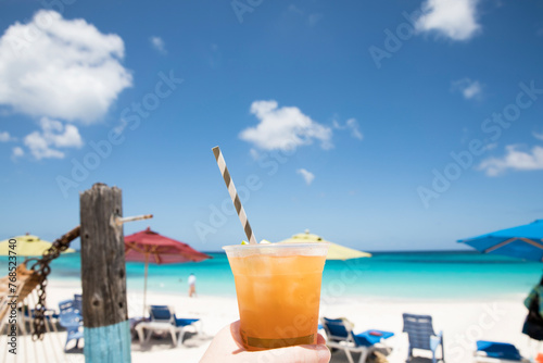 Tropical Drink With Striped Straw Held Up Against Blue Caribbean Sky