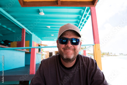 Smiling Man in Sunglasses on Vacation at Colorful  Caribbean Beach Bar photo