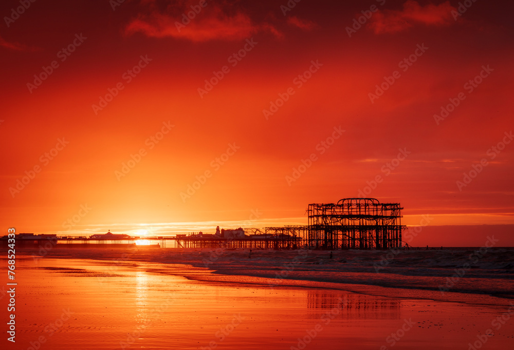 Brighton West  Pier and Palace Pier during a very vibrant red dawn on the east Sussex coast south east England UK