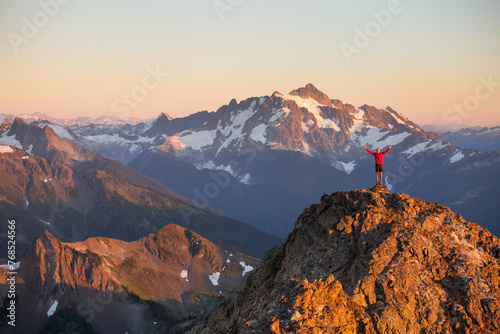 Hiker stands and raises arms on summit after successful hike photo