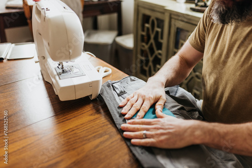 Man sits at kitchen table with sewing machine patching work pants photo