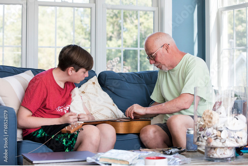Grandfather and Grandson Work Together To Restring Guitar at Home photo