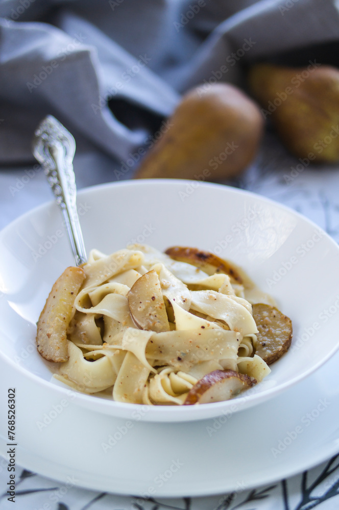 Dish featuring pasta, pears, and spoon, with a creamy bchamel sauce