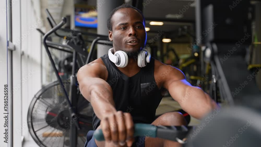 Rowing with power. Man training rowing machine in gym Rowing with power. Man training rowing machine in gym