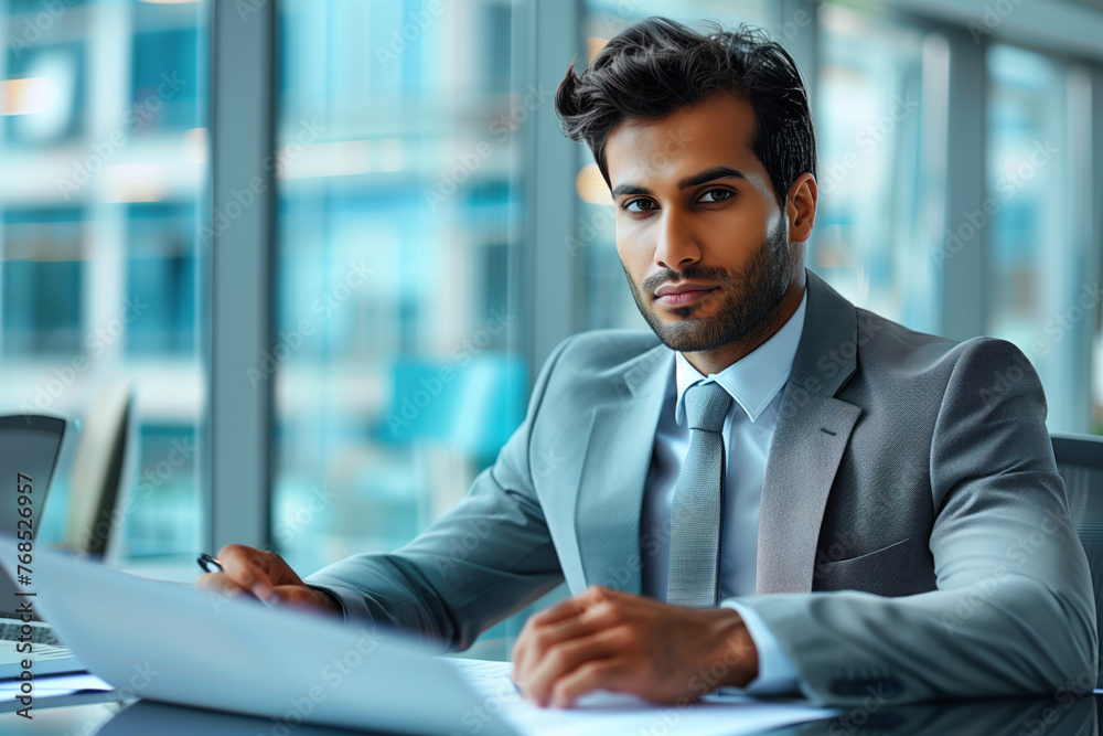 Confident businessman reviewing documents in a modern corporate office.