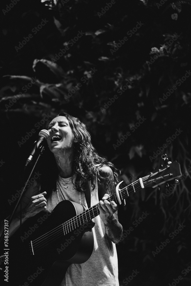Young woman singer, sings into a microphone and plays the guitar. Young woman singer, sings into a microphone and plays the guitar.