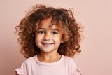 Portrait of a cute little girl with curly hair against pink background
