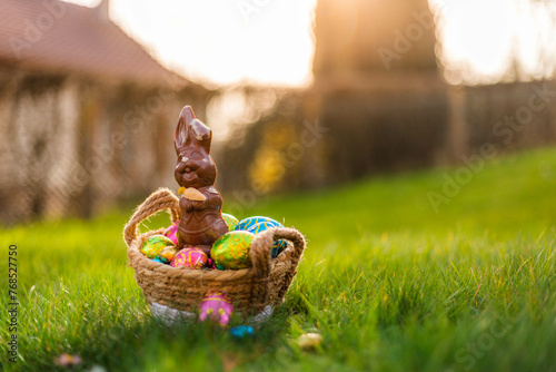 Easter eggs in basket in grass. Colorful decorated easter eggs in wicker basket. Traditional egg hunt for spring holidays. Morning magical light photo