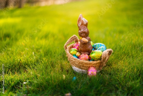 Easter eggs in basket in grass. Colorful decorated easter eggs in wicker basket. Traditional egg hunt for spring holidays. Morning magical light