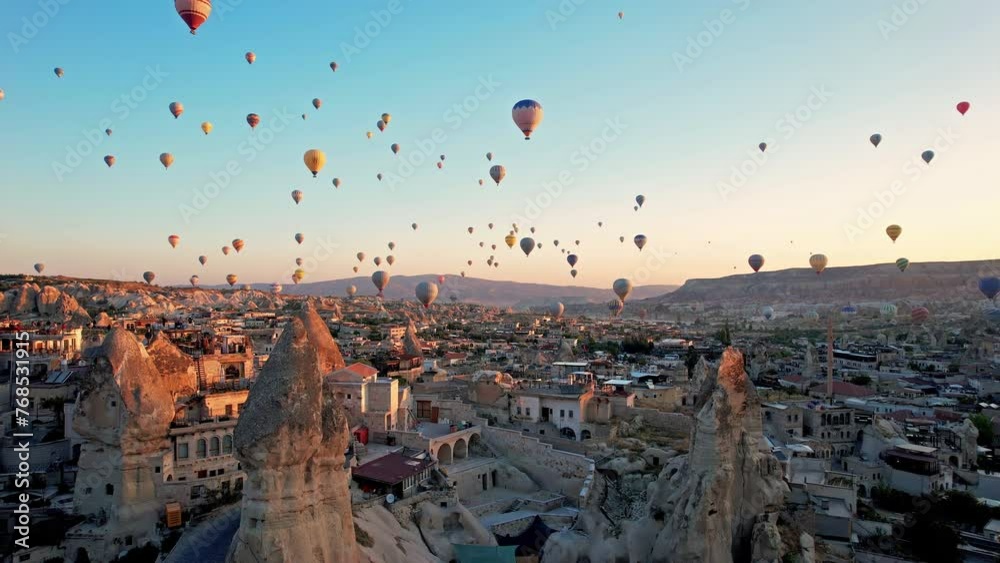 Aerial view of colorful hot air balloons in Cappadocia, Turkey, fly in the sky over a mountain valley at summer sunrise. The vibrant balloons rise gracefully over the valley, Goreme