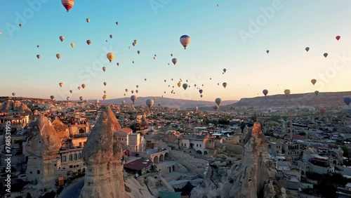 Aerial view of colorful hot air balloons in Cappadocia, Turkey, fly in the sky over a mountain valley at summer sunrise. The vibrant balloons rise gracefully over the valley, Goreme photo