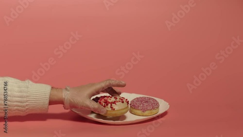 Close up of hand putting donuts on the plate. Three round donuts on the whote plate. Food. Desert. 
