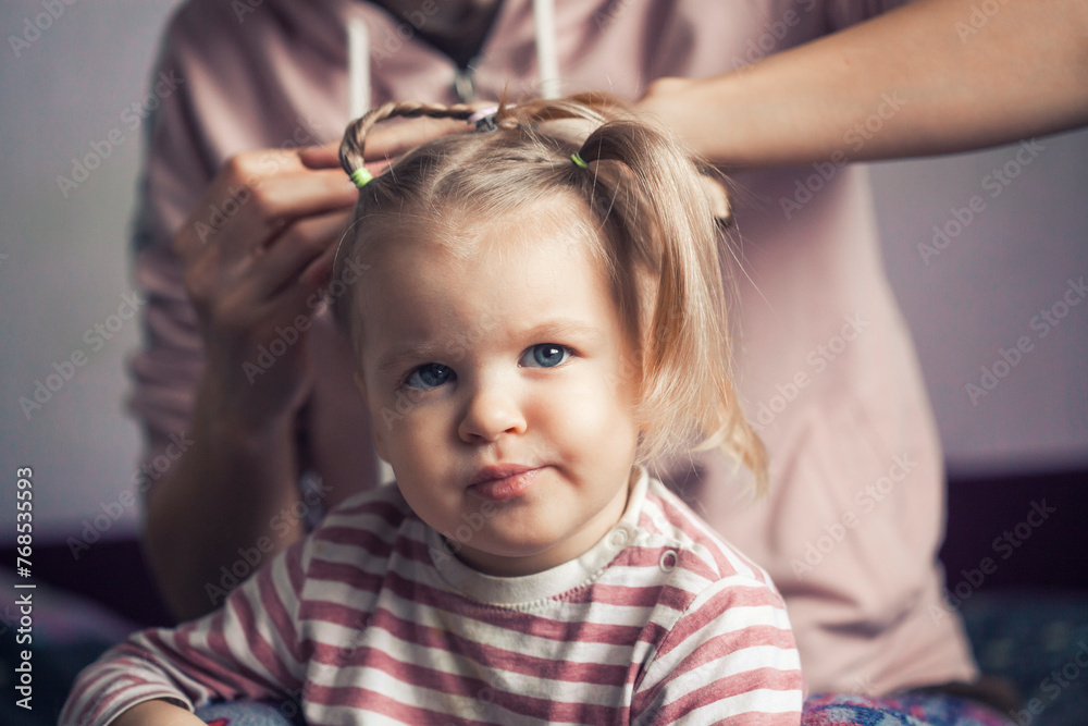 Mom braids her little daughter's hair